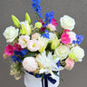 flowers arranged in a white hatbox with a grey background 